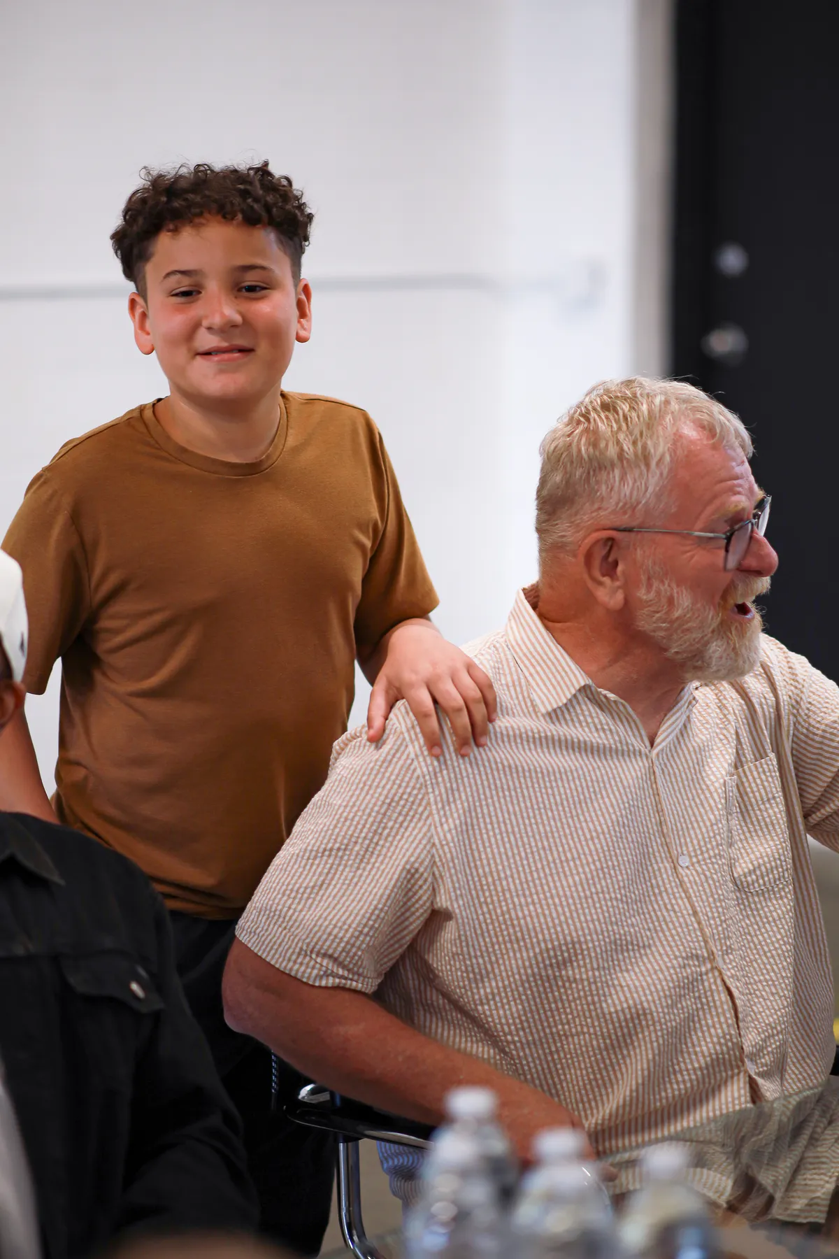 A boy greeting an older friend at the table