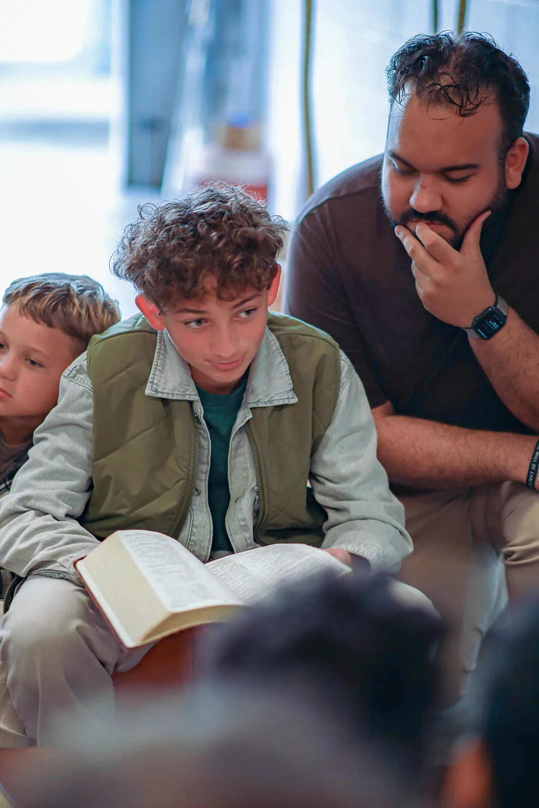 A young man reading Scripture with friends around him