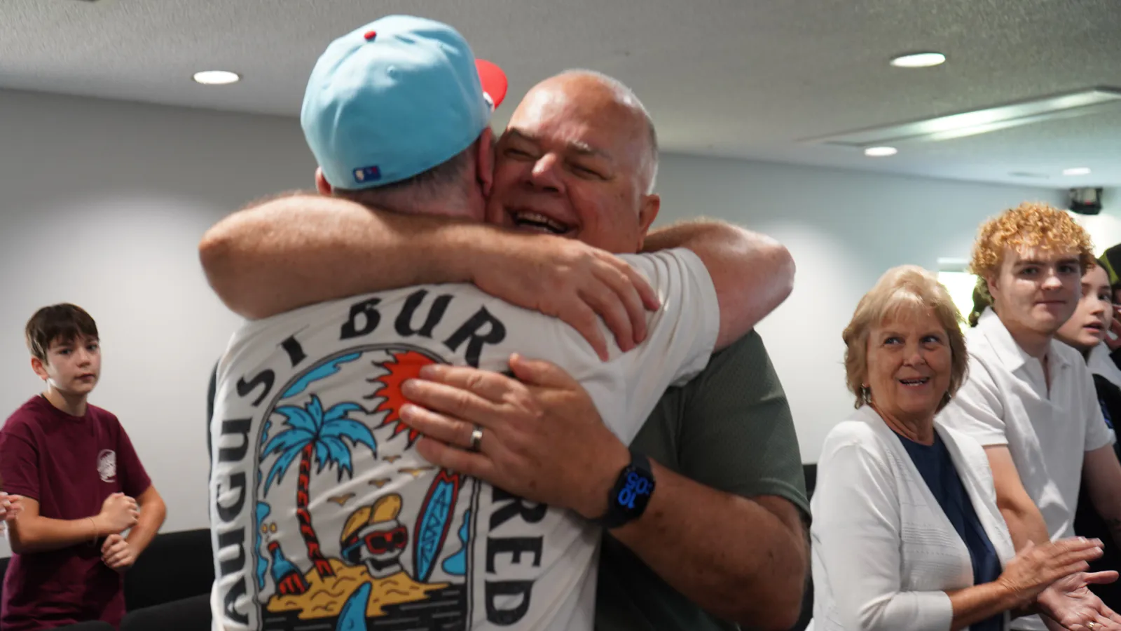 Two men sharing a big hug on a Sunday morning while others smile around them