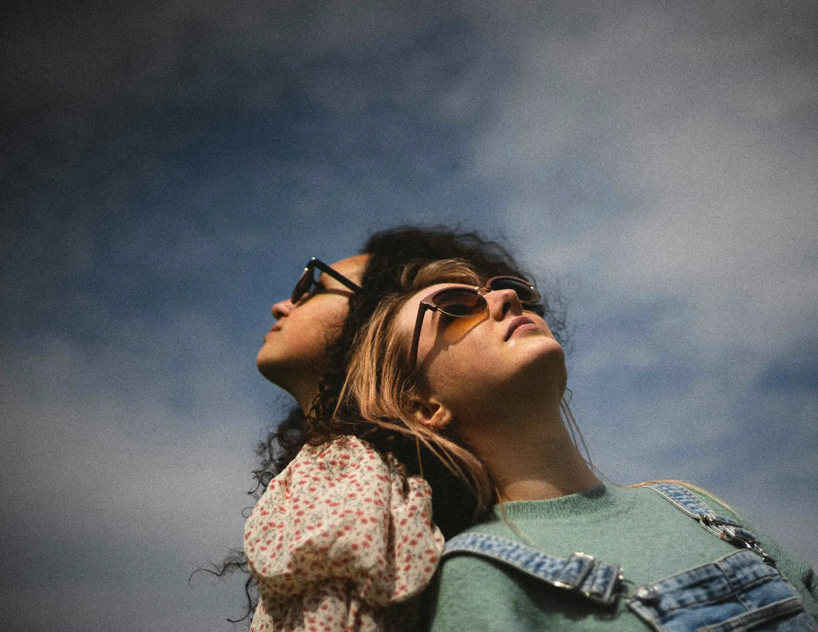 Two students in sunglasses looking up at the sky